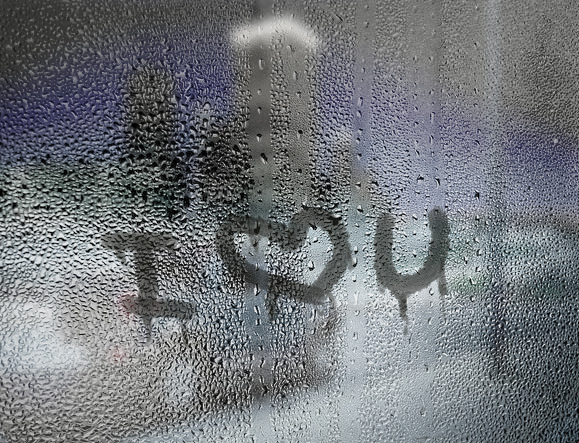 write your text, message or logo on a wet window pane with raindrops